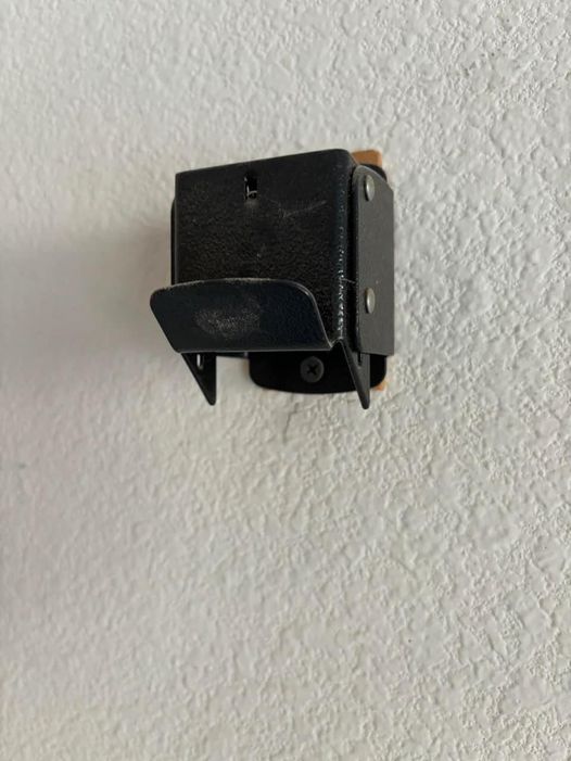 I saw this on the wall of the garage when I moved into this house. It appears to be a metal belt buckle, possibly serving as a stand.