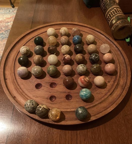 1ft-diameter wooden disk with 37 moveable marbles (1 inch diameter). 37 divots in the center, and a ring on the rim.