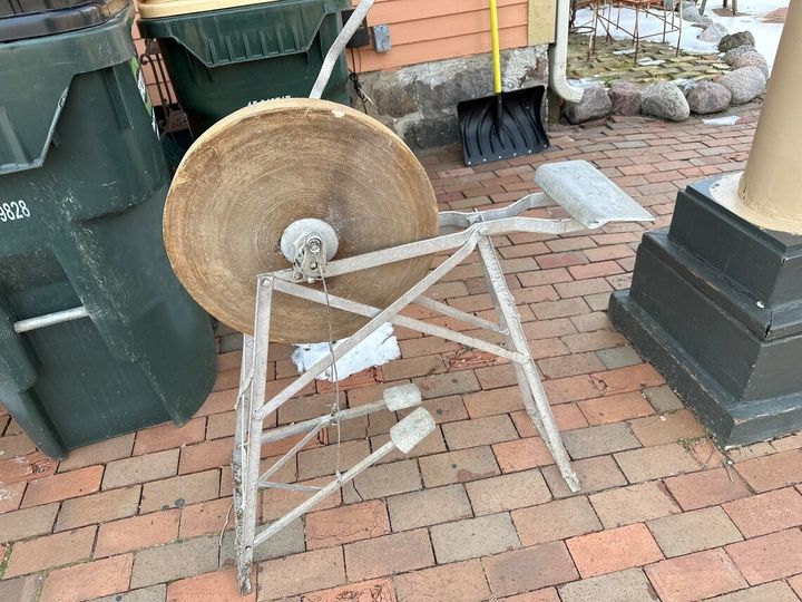 Can anyone identify this? I’m at a holiday cottage, and this is in the garden. It’s mostly metal, has a pedal attached to a large cog with a bolt above it, and looks very old