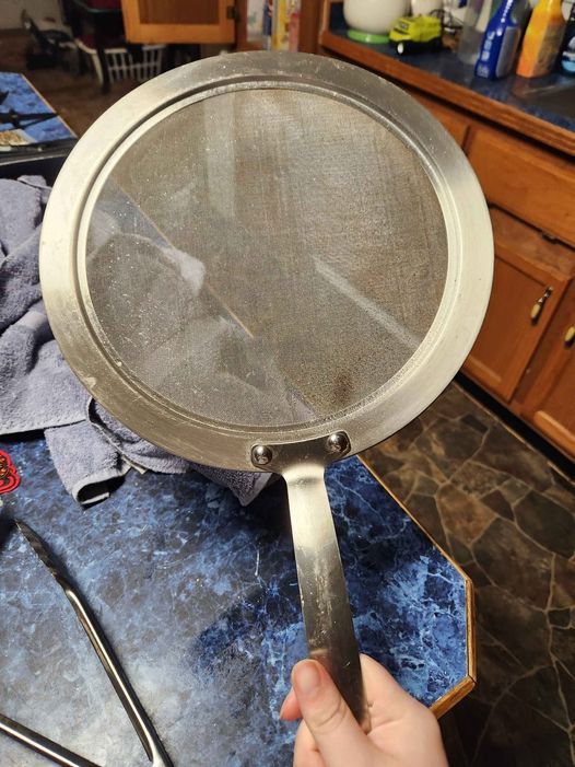 Found in a storage area with multiple pots and pans, a circular metal piece that includes a fine mesh screen.